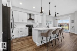 Contemporary kitchen featuring white cabinetry, subway tile backsplash, and a central island with a sink and pendant lighting - 
