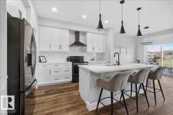 Modern kitchen featuring white cabinetry, a large center island with seating, dark wood-finish flooring, a white subway tile backsplash, and stainless steel appliances - 