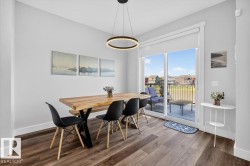 Bright dining area featuring wood-finish flooring, a contemporary circular pendant light, and sliding glass doors opening to an exterior deck - 