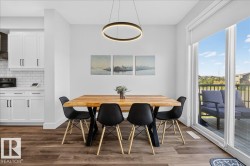 Open-concept dining area featuring wood-finish flooring, a contemporary circular pendant light, and sliding glass doors leading to a private deck - 