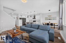 Open-concept living area featuring wood-finish flooring, white walls, and recessed lighting - 