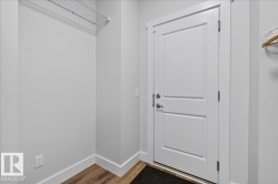 Entryway featuring a paneled door with brushed nickel hardware, wood-finish flooring, and crisp white baseboards - 