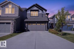 Two-story residence featuring a dark gray facade with contrasting siding accents, an attached two-car garage, and a concrete driveway - 