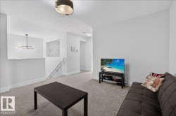 Carpeted upper-level space featuring a contemporary linear chandelier, recessed wall niche, and an open railing overlooking a lower area - 
