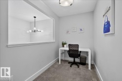 Dedicated flex space featuring neutral carpeting, a pass-through window with a modern chandelier, and contemporary light gray wall paint - 