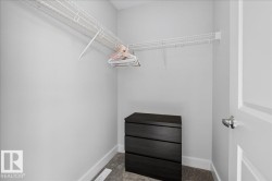 Walk-in closet featuring white wire shelving, gray carpet, white baseboards, and a white interior door with brushed nickel hardware - 