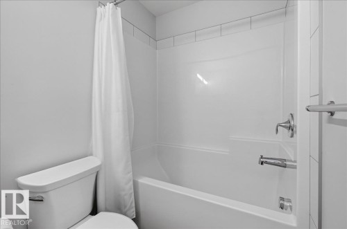 White bathtub-shower combination with a tiled surround - 3805 Cherry Loop Sw, Edmonton, AB - Indoor Photo Showing Bathroom