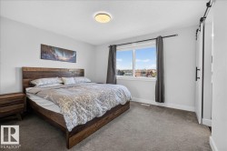 Bedroom featuring a large window, soft grey carpeting, and a modern ceiling light fixture - 