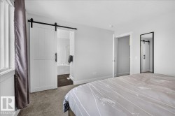 Barn door entry to an en-suite bathroom featuring a white soaking tub and dual vanities - 