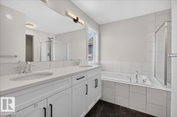 Double vanity with white cabinetry and black hardware, set against a large mirror - 
