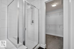 Spacious shower enclosure with glass surround and white tilework - 