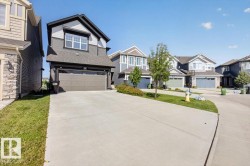 Contemporary residential exterior featuring a two-car garage, concrete driveway, and gabled roofline - 