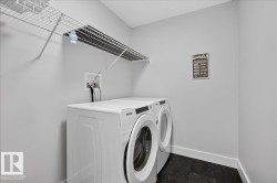 Dedicated laundry area featuring a washer and dryer, dark-toned flooring, light gray walls, and upper wire shelving for storage - 