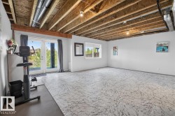 Spacious room featuring exposed ceiling joists and ductwork, white walls, and light-patterned flooring - 
