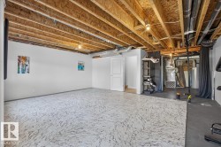 Open unfinished basement area featuring exposed ceiling joists, light-colored patterned flooring, and white painted walls - 