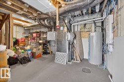 Unfinished basement featuring exposed wood joists and structural beams, ductwork, a water heater, and a furnace unit - 