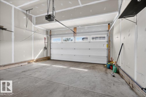 Attached two-car garage featuring a concrete floor, automatic garage door opener, and integrated transom windows - 3805 Cherry Loop Sw, Edmonton, AB - Indoor Photo Showing Garage
