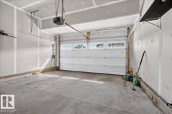 Attached two-car garage featuring a concrete floor, automatic garage door opener, and integrated transom windows - 