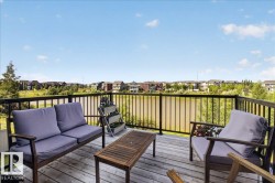 Expansive outdoor deck featuring wood-finish flooring and black metal railings - 