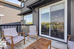 Outdoor deck featuring wood-finish flooring, black metal railings, and a large sliding glass door - 