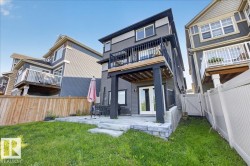 Rear exterior featuring gray siding, a second-story balcony with dark railings, and a ground-level patio - 