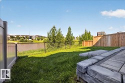 Expansive backyard featuring a stone paver patio, lush green lawn, and mature trees - 