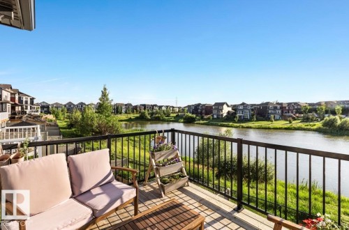 Expansive outdoor deck featuring wood-finish flooring and black metal railings - 3805 Cherry Loop Sw, Edmonton, AB - Outdoor With Body Of Water