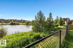 Chain-link perimeter fencing with a natural water feature and mature vegetation - 