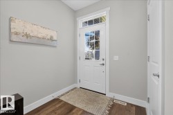 Entryway featuring a white paneled door with glass inserts and a transom window, wood-finish flooring, light gray walls, white baseboards, and a white interior door - 