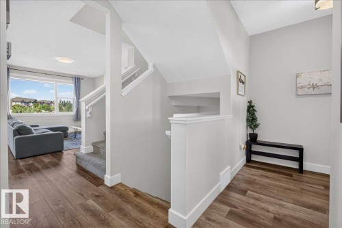 Warm wood-finish flooring extending into the open-concept living area - 3805 Cherry Loop Sw, Edmonton, AB - Indoor Photo Showing Other Room