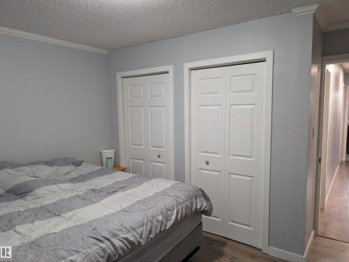 Bedroom featuring light gray walls, white crown molding, and two sets of white bi-fold closet doors - 14228 22 Street Nw, Edmonton, AB - Indoor Photo Showing Bedroom