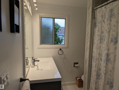 Contemporary bathroom featuring a white vanity with an integrated rectangular sink, matte black faucet, and coordinating towel ring - 14228 22 Street Nw, Edmonton, AB - Indoor Photo Showing Bathroom