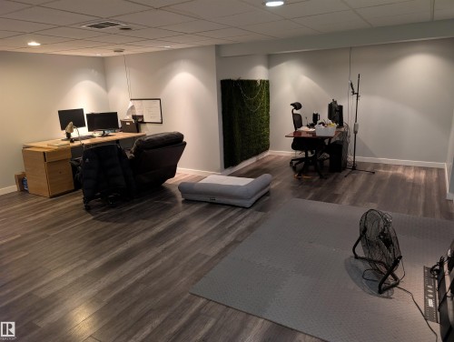 Spacious room featuring wood-finish flooring, light grey painted walls, recessed lighting, and a suspended ceiling with visible ventilation - 14228 22 Street Nw, Edmonton, AB - Indoor
