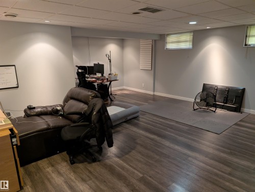 Recessed lighting illuminates the spacious room featuring wood-finish flooring, light gray wall paint, and a drop ceiling - 14228 22 Street Nw, Edmonton, AB - Indoor