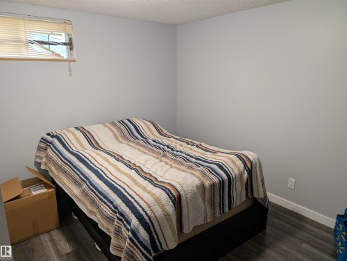 Room featuring wood-finish flooring, a window with blinds, light-colored walls, white baseboards, and a textured ceiling - 14228 22 Street Nw, Edmonton, AB - Indoor Photo Showing Bedroom