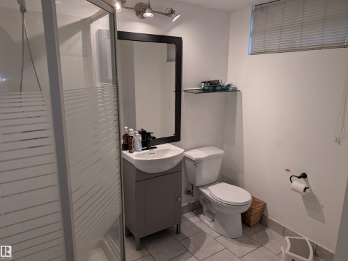 Compact bathroom featuring a glass-enclosed shower, a modern vanity with integrated sink, a sleek black-framed mirror, and track lighting - 14228 22 Street Nw, Edmonton, AB - Indoor Photo Showing Bathroom