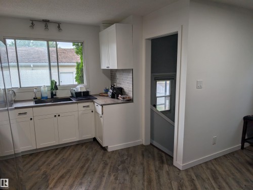 Modern kitchen featuring white cabinetry with black hardware, wood-finish countertops, and a subway tile backsplash - 14228 22 Street Nw, Edmonton, AB - Indoor Photo Showing Kitchen