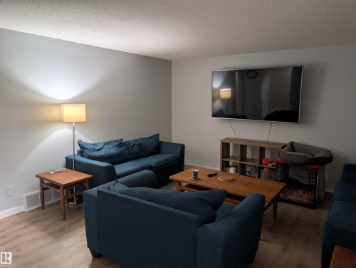 Spacious living area featuring light-toned wall paint and wood-finish flooring - 14228 22 Street Nw, Edmonton, AB - Indoor Photo Showing Living Room