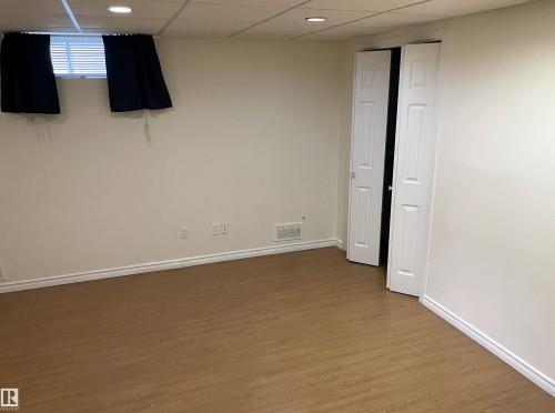 Spacious room featuring wood-finish flooring, light-toned walls, bi-fold doors, white baseboards, and recessed ceiling lighting - 11308 73 Avenue Nw, Edmonton, AB - Indoor Photo Showing Other Room