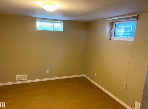 Versatile room featuring wood-finish flooring, neutral-toned walls, and white baseboards - 11308 73 Avenue Nw, Edmonton, AB - Indoor Photo Showing Other Room