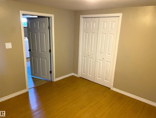 Room featuring wood-finish flooring, neutral wall paint, white baseboards, and a white bi-fold closet - 11308 73 Avenue Nw, Edmonton, AB - Indoor Photo Showing Other Room