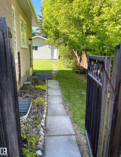 Expansive backyard featuring a stone paver pathway, mature trees, and a detached auxiliary structure with horizontal siding - 11308 73 Avenue Nw, Edmonton, AB - Outdoor