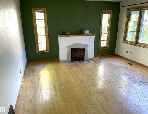 Light wood-finish flooring complements the fireplace with an integrated electric insert - 11308 73 Avenue Nw, Edmonton, AB - Indoor Photo Showing Living Room With Fireplace