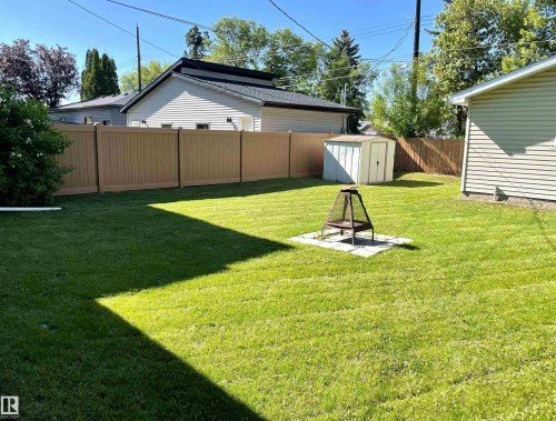 Expansive lawn area featuring a fire pit on a concrete pad - 11308 73 Avenue Nw, Edmonton, AB - Outdoor With Backyard