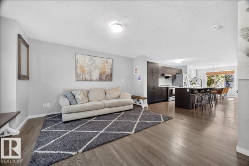 Open-concept living space featuring wood-finish flooring, recessed lighting, and light gray wall tones - 3043 Keswick Way Sw, Edmonton, AB - Indoor Photo Showing Living Room