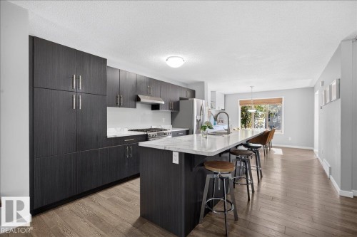 Kitchen featuring dark wood-finish cabinetry, stainless steel appliances, and a gas range - 3043 Keswick Way Sw, Edmonton, AB - Indoor Photo Showing Kitchen With Upgraded Kitchen