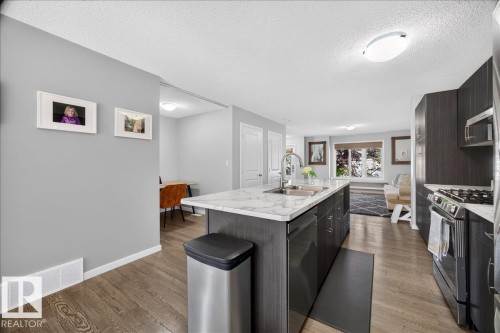Kitchen island featuring a double-basin sink, gooseneck faucet, and integrated dishwasher - 3043 Keswick Way Sw, Edmonton, AB - Indoor Photo Showing Kitchen With Upgraded Kitchen