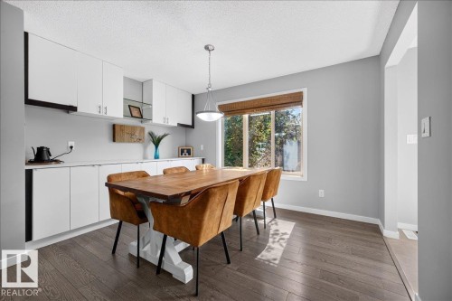 Expansive dining area featuring wood-finish flooring, a contemporary pendant light fixture, and a large window with a woven shade - 3043 Keswick Way Sw, Edmonton, AB - Indoor