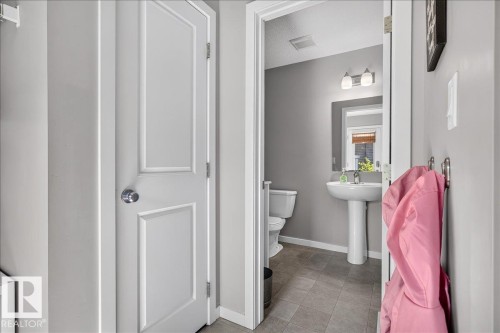 Hallway featuring light gray wall paint, white trim, and a paneled interior door with a chrome knob - 3043 Keswick Way Sw, Edmonton, AB - Indoor