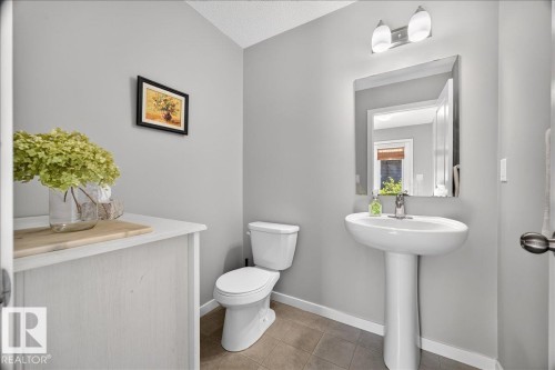 Pedestal sink with chrome hardware and an overhead vanity light fixture - 3043 Keswick Way Sw, Edmonton, AB - Indoor Photo Showing Bathroom